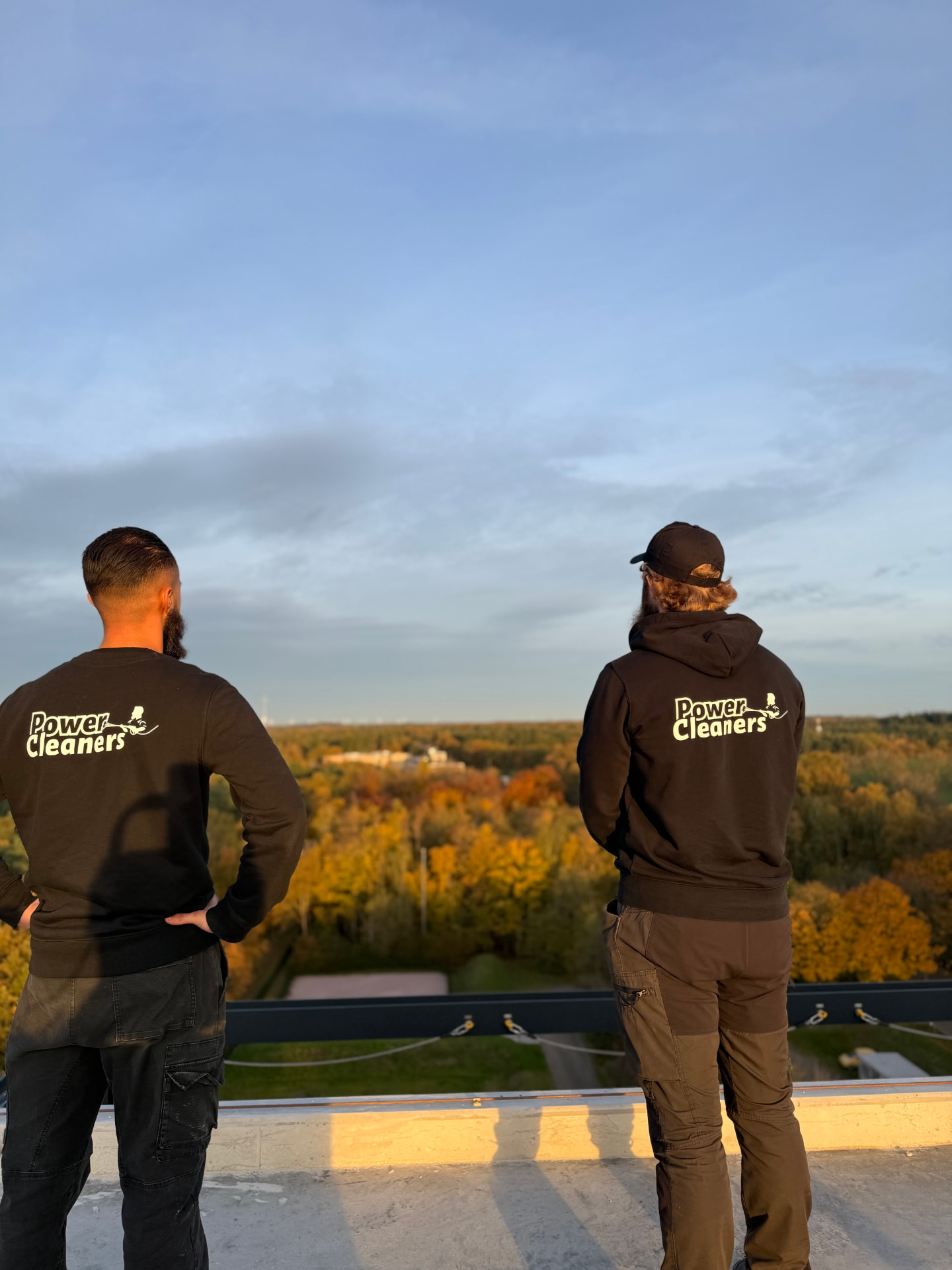 Joey en Mats van PowerCleaners op een dak, uitkijkend over het landschap